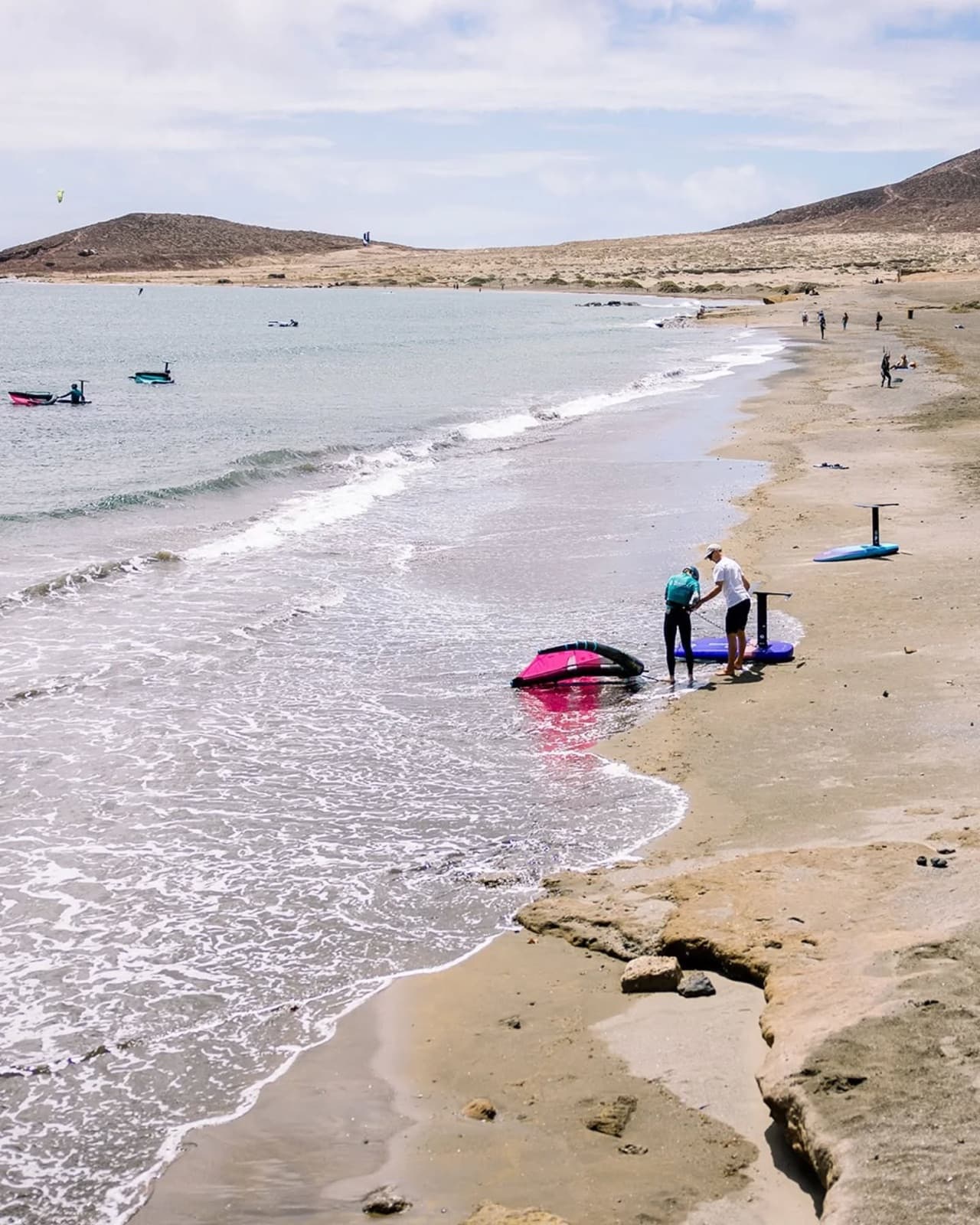 A coach helping a rider set up on the beach at El Médano