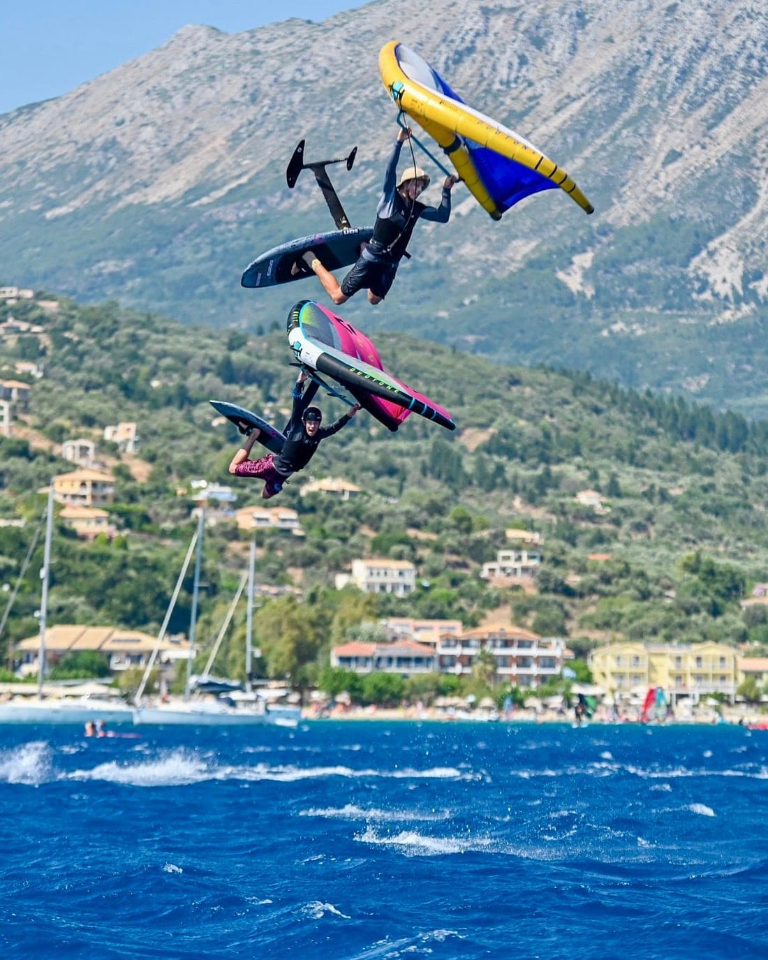 Two wing foilers jumping in front of Vassiliki village