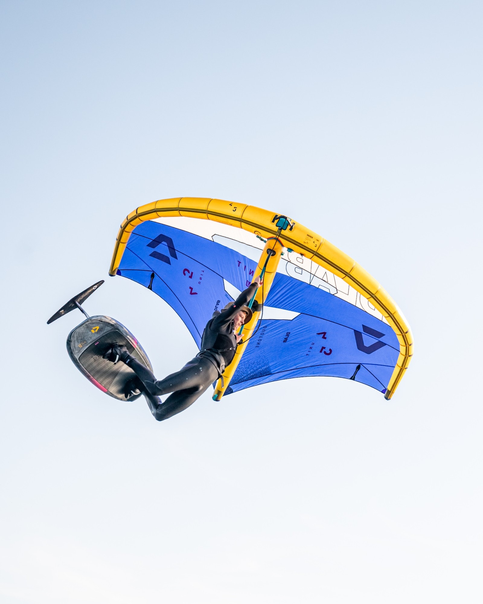 Toby Cunliffe upside down mid-air with his wing and foil board