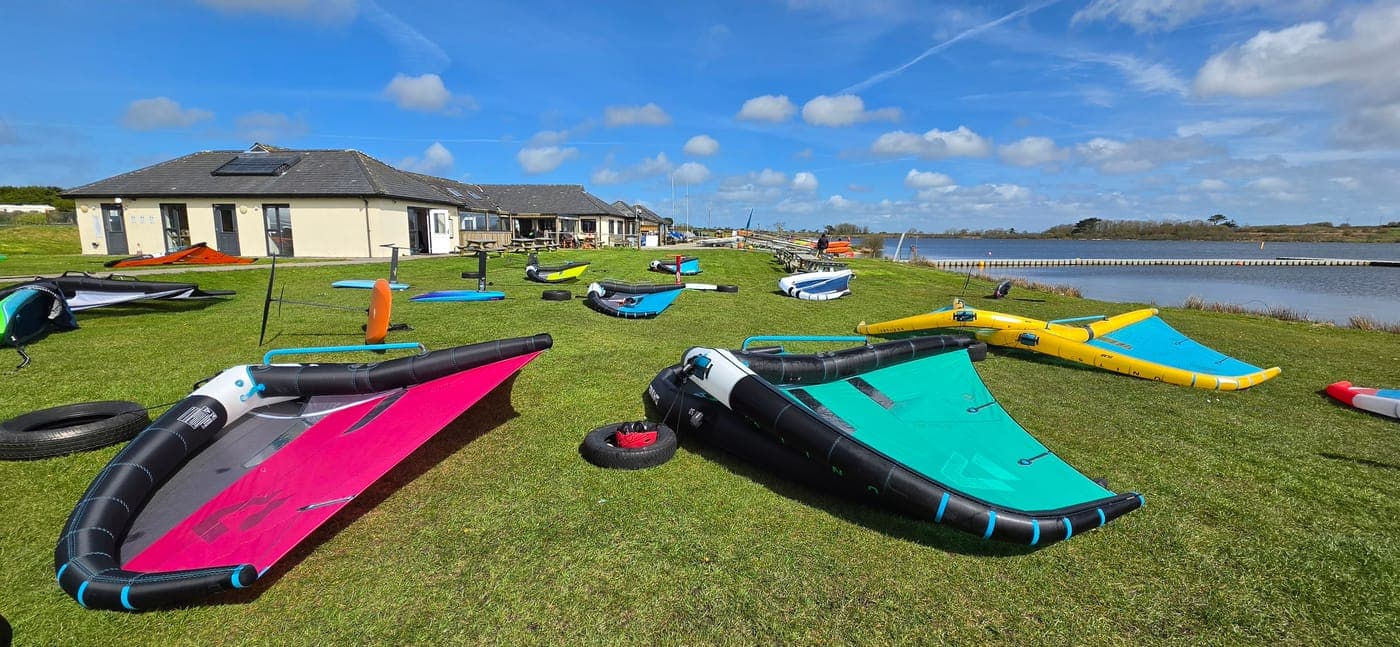 Wings and boards laid out on the grass by the lake at Stithians